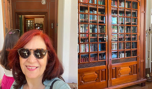 Selfie Deusa Rodrigues, com uma estante de livros ao fundo e uma porta aberta.