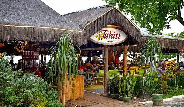 Restaurante Tahiti com ambiente tropical, decorado com palmeiras e mesas coloridas, ideal para refeições à beira-mar.