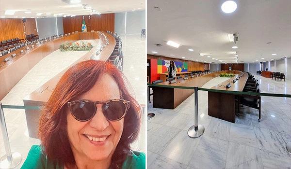 Imagem de uma sala de reuniões formal, com uma mesa longa e cadeiras, decorada com elementos verdes e a bandeira brasileira ao fundo. Dessa forma, a sala é projetada para encontros importantes e discussões administrativas. Dicas sobre a visita ao Palácio do Planalto.