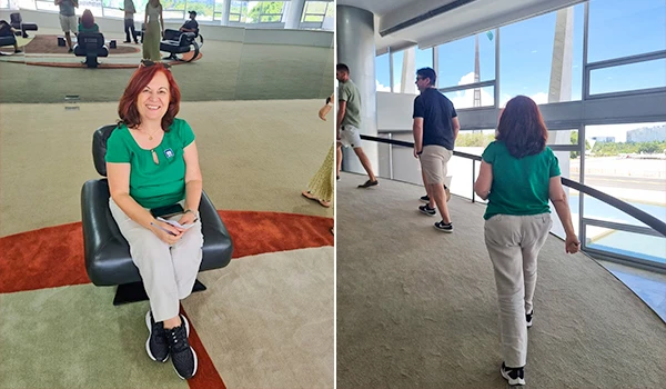 Deusa Rodrigues sentada em uma cadeira em um ambiente amplo e iluminado, com pessoas subindo a rampa interna do Palácio do Planalto. Ela está usando uma camiseta verde e calças claras.