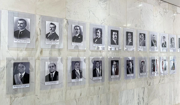 Painel histórico com retratos de líderes e figuras importantes em preto e branco, exibindo suas identidades e contribuições significativas ao longo do tempo.