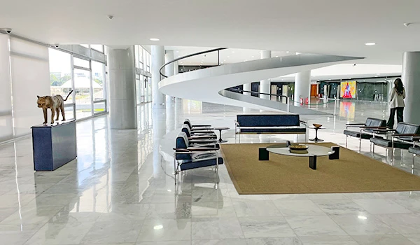 Imagem de um hall moderno com decoração minimalista, incluindo um poste com uma escultura de um animal e móveis elegantes em um ambiente iluminado.