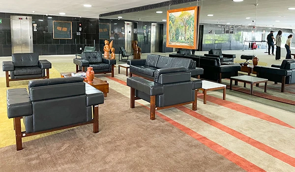 Sala de estar moderna e elegante com sofás de couro preto, mesas de centro e obras de arte na parede, criando um ambiente aconchegante e contemporâneo.