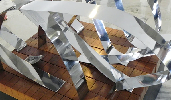 Escultura moderna em metal e madeira com formas abstratas, destacando a interação entre materiais e texturas, perfeita para decoração contemporânea.
