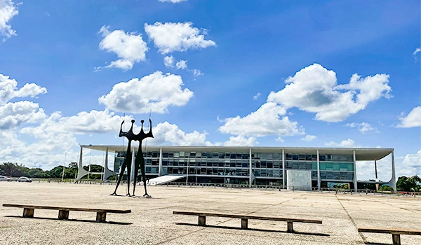 Imagem do Palácio do Planalto, sede do governo brasileiro, com esculturas em frente e céu azul. Um ícone da arquitetura moderna no Brasil.