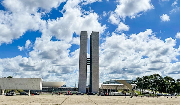 Vista do Congresso Nacional em Brasília, destacando a arquitetura moderna e o céu azul com nuvens. Um ícone da política brasileira.