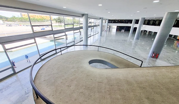 Vista interna da rampa interna no Palácio do Planalto, com piso de mármore e janelas amplas. O local é ideal para eventos e exposições, destacando a arquitetura contemporânea.