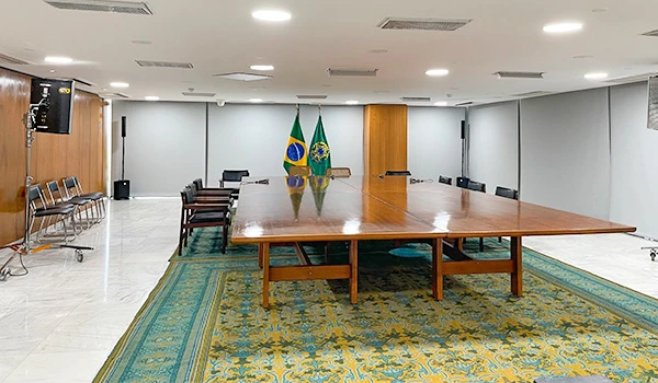 Sala de reuniões com mesa grande, bandeiras do Brasil e decoração simples, ideal para eventos e encontros oficiais. Dicas sobre a visita ao Palácio do Planalto.