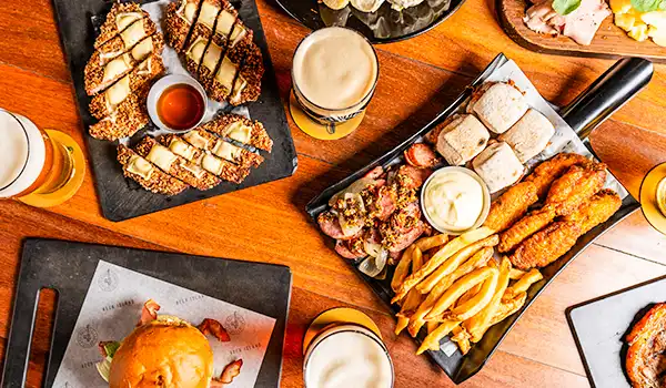Deliciosa combinação de pratos em uma mesa, incluindo fritas, carnes e acompanhamentos, ideal para amantes de uma boa refeição e cerveja. Um dos presentes para o Dia das Mães com gastronomia.