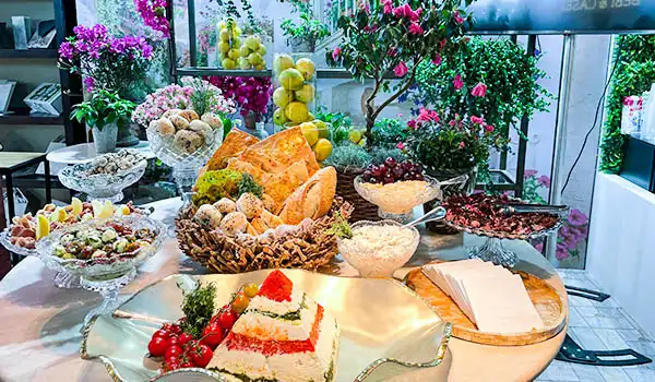 Mesa de festa com bolo, doces e flores decorativas, ideal para comemorações especiais, com uma variedade de sobremesas e elementos florais vibrantes em um ambiente bem decorado.