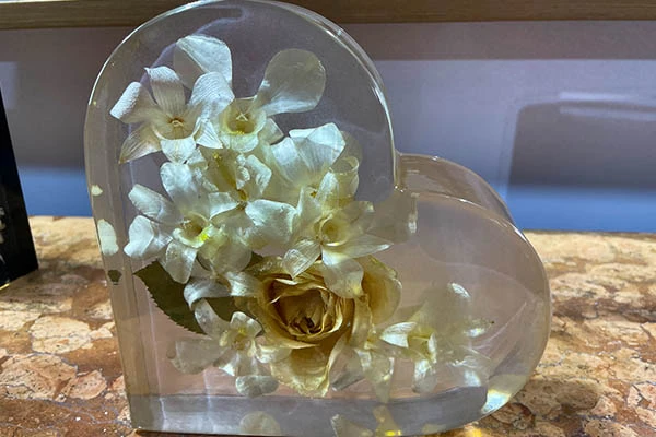 Buquê de flores de rosas e orquídeas preservadas em coração de transparente, decoração elegante para ocasiões especiais.