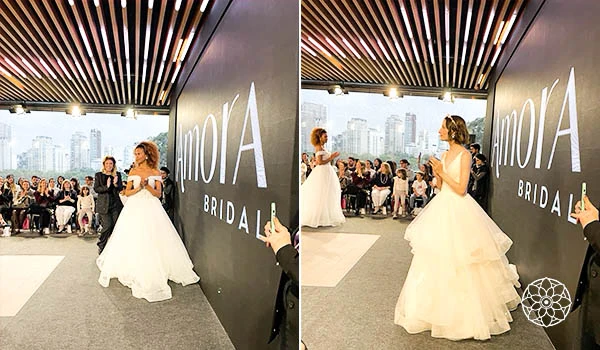 Casamento com noiva vestida de branco em evento especial, cercada por convidados, com decoração elegante e uma parede com a palavra 'Noiva' ao fundo.