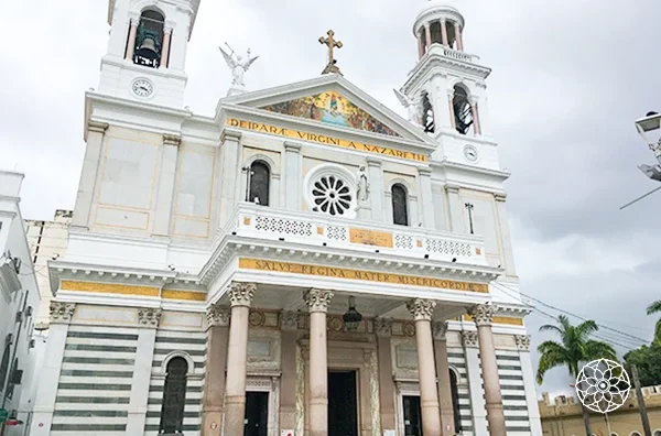 Imagem da fachada de uma igreja católica com arquitetura clássica, colunas, torres e cruz no topo, localizada na cidade de Natal, Rio Grande do Norte, Brasil.