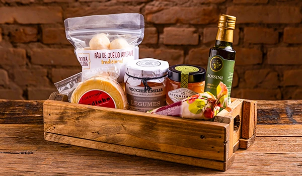 Cesta de produtos artesanais com queijo, legumes em conserva e azeite, ideal para quem aprecia sabores tradicionais. Uma seleção perfeita como um dos presentes para o Dia das Mães com gastronomia.