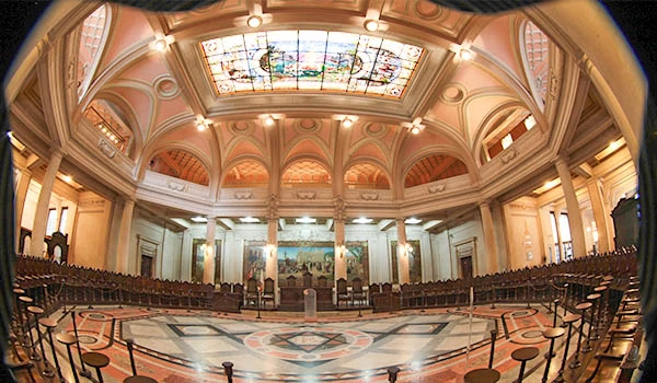 Vista panorâmica do interior de um templo, com detalhes arquitetônicos impressionantes e vitrais coloridos. O ambiente é amplo e iluminado, ideal para eventos. A atmosfera é majestosa e histórica, refletindo a cultura local.