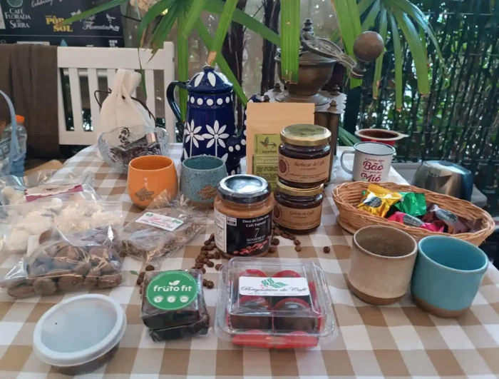 Variedade de produtos naturais e gourmet para chá, incluindo chás, café, chocolates, mel, canecas e utensílios, em ambiente aconchegante rústico.