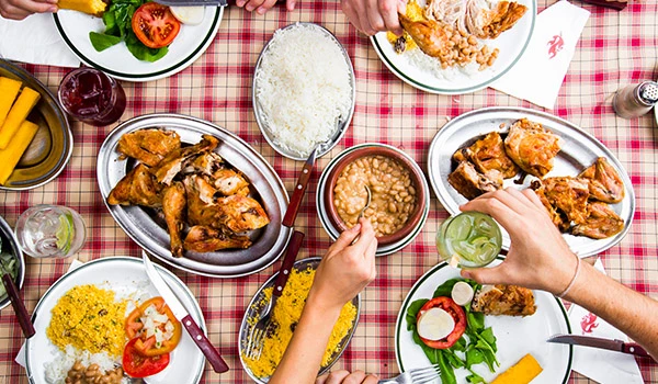 Mesa repleta com pratos variados, incluindo frango assado, arroz, feijão, saladas e acompanhamentos, ideal para um almoço saboroso. Ótima opção para presentes do Dia das Mães gastronomia.