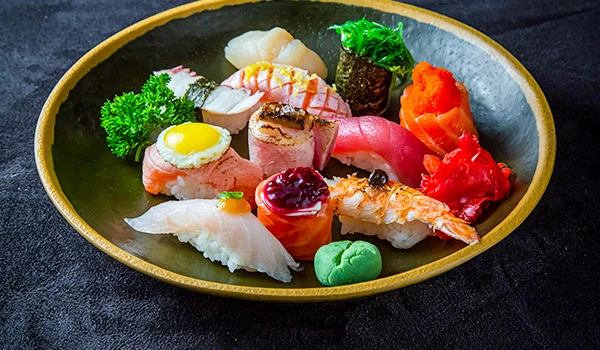 Prato de sushi variado com nigiri, sashimi e guarnições em um elegante prato redondo. Delícias da culinária japonesa um dos presentes para o Dia das Mães com gastronomia.