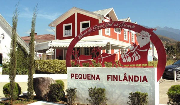 Entrada da cidade Pequena Finlândia em Penedo, Rio de Janeiro, com decoração natalina de Papai Noel e cenário de casas coloridas, ideal para turismo familiar e clima de Natal.