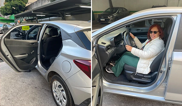 Deusa Rodrigues dentro de um carro usando óculos de sol, sentada no banco do motorista em uma cena ao ar livre, com foco na experiência de dirigir com segurança e conforto.