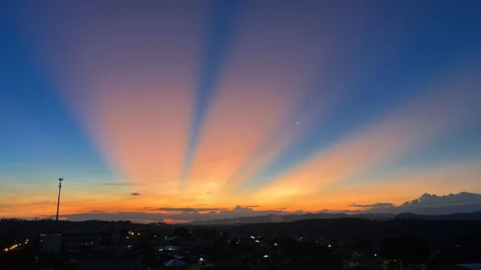 Céu ao pôr do sol com impressionantes raios crepusculares se estendendo sobre o horizonte, criando uma cena natural de beleza e tranquilidade.