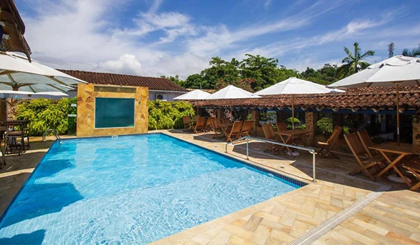 Piscina no clima tropical com espreguiçadeiras, guarda-sóis e árvores ao redor em um resort ou centro de lazer ao ar livre no Brasil.