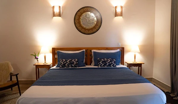 Quarto aconchegante com cama grande, cabeceira de madeira, almofadas decorativas e iluminação suave, ideal para relaxar.