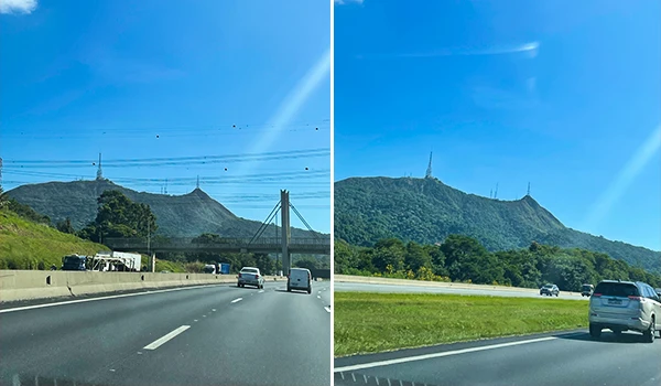 Paisagem de estrada com montanhas ao fundo sob céu azul claro e trânsito de veículos, destacando o horizonte e a natureza em dia ensolarado.