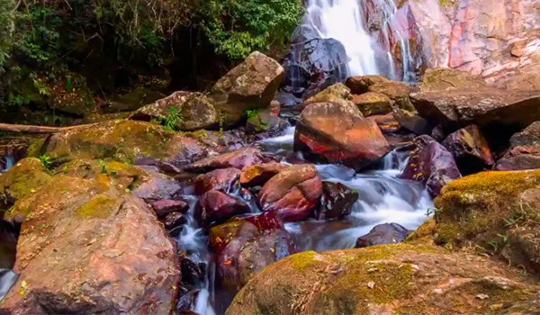 Cachoeira e pedras no rio rodeado por vegetação, cenário natural exuberante para momentos de tranquilidade ao ar livre. Lugares com cachoeira no Brasil.