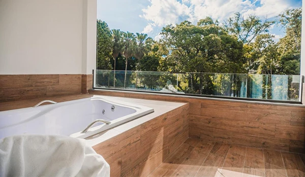 Banheira de hidromassagem na varanda com vista para a natureza, espaço de relaxamento e bem-estar em ambiente confortável e elegante.