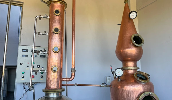 Imagem de uma destilaria artesanal com caldeiras de cobre, válvulas e manômetros usados na produção de destilados como aguardente. Rotas Gastronômicas do interior de SP.