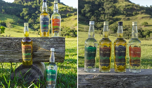 Imagem de cinco garrafas de cachaça artesanais de diferentes tamanhos e rótulos, colocadas sobre troncos de árvores ao ar livre, com natureza ao fundo.