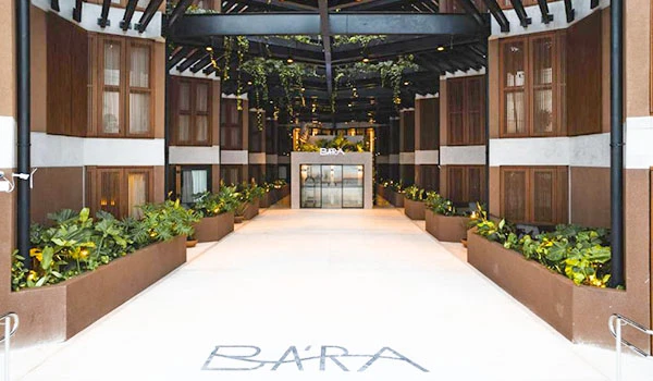 Ambiente interno elegante de um restaurante com plantas decorativas ao longo das paredes, iluminação moderna e espaço amplo, ideal para jantares sofisticados. Um lugares para comemorar Bodas de Prata no Brasil.