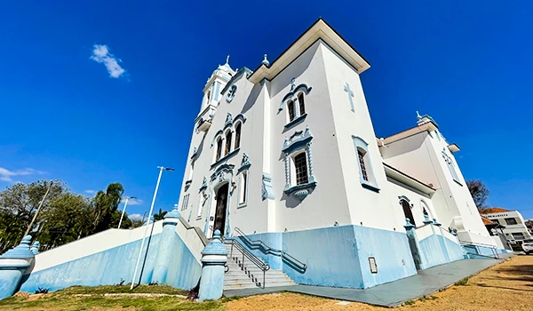 Imagem de uma igreja histórica com arquitetura colonial branca, detalhes ornamentais e um céu azul claro ao fundo. Perfeita para visitar ou conhecer sua história.