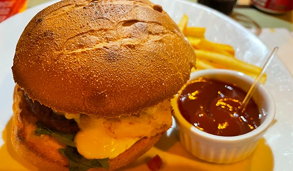 Hambúrguer de carne, queijo, alface e pão, acompanhado de batatas fritas e molho barbecue em uma refeição deliciosa e apetitoso.
