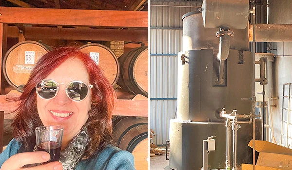 Deusa Rodrigues, brindando com uma taça de licor, no Engenho Bessi, com barris de madeira ao fundo. Rotas Gastronômicas do interior de SP.