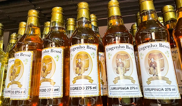 Imagem de garrafas do licor Engenho Bessi, sabor Jurupinga, com rótulos que destacam a tradição artesanal brasileira, 275 ml.