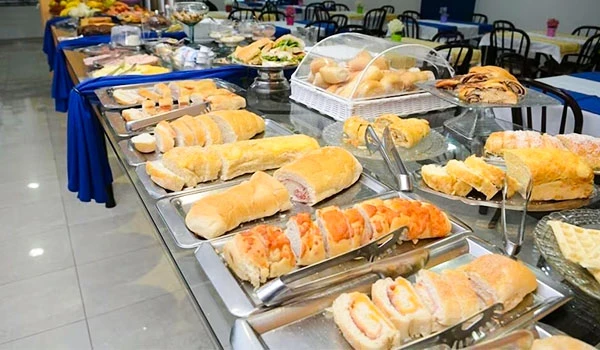 Buffet com diversas opções de pão, queijo, frios e salgados em uma sala de eventos, hotel de Botucatu. Rotas Gastronômicas do interior de SP.