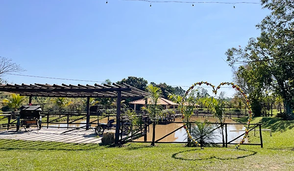 Paisagem rural com lago, área de lazer ao ar livre, árvores, jardim e espaço de convivência em um ambiente tranquilo e natural.
