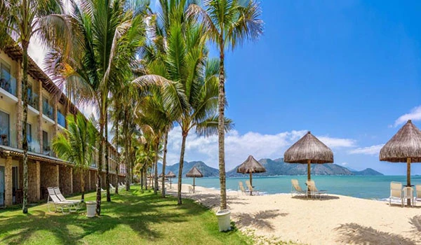 Beira-mar paradisíaca com cabanas de praia e muitas palmeiras, um lugares para comemorar Bodas de Prata no Brasil.