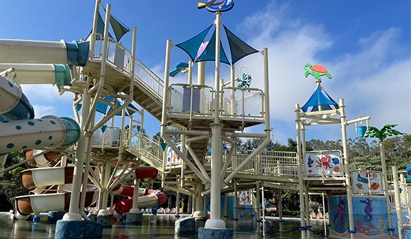 Área de parque aquático com escorregadores e estruturas de diversão sob céu azul, ideal para lazer e entretenimento infantil ao ar livre.