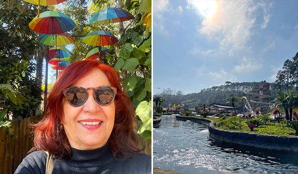 Deusa Rodrigues ao ar livre, com guarda-chuvas coloridos pendurados acima dela e paisagem ao fundo.