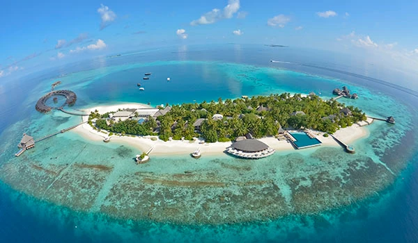 Imagem aérea de uma ilha paradisíaca com águas cristalinas, praias de areia branca, vegetação exuberante, resorts e infraestrutura de turismo em um cenário tropical.