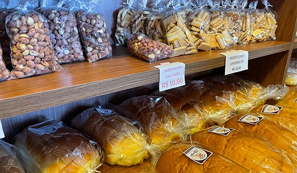 Variedade de doces artesanais embalados a vácuo na padaria, com destaque para amendoim salgado e doces tradicionais de fabricação local.