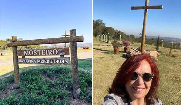 Imagem do Padrão de cruz em Mosteiro da Divina Misericórdia com vista de natureza, mostrando Deusa Rodrigues com óculos ao lado de um grande símbolo religioso ao ar livre, numa paisagem de campo e céu claro. O que fazer em Marília.