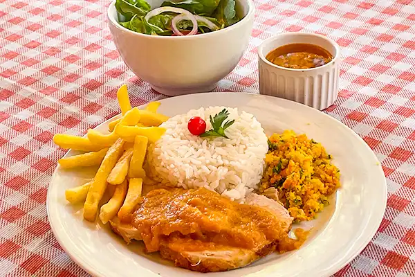 Prato típico brasileiro com arroz, feijão, salada, lombo assado, farofa e molho, servido em mesa com guardanapo de xadrez vermelho e branco. Rotas Gastronômicas do interior de SP.