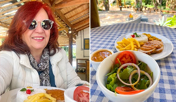 Deusa Rodrigues, desfrutando de uma refeição ao ar livre em um ambiente rústico com comida típica brasileira.