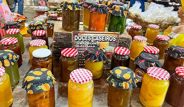 Doces caseiros em potes variados, incluindo geleias de frutas, com etiquetas decorativas. Rotas Gastronômicas no Interior SP.
