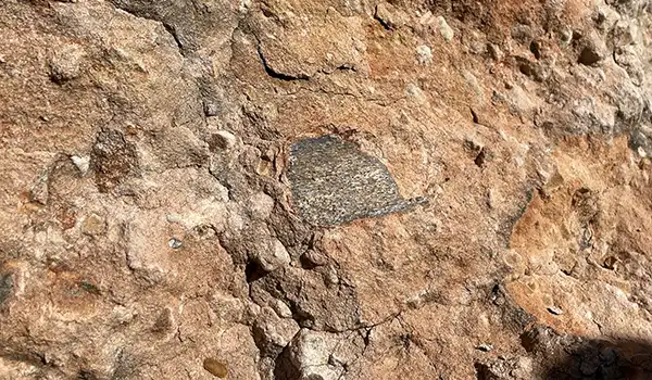 Imagem de uma superfície de terra com textura irregular, cheia de pequenas pedras e fragmentos de barro, adequada para estudos paleontologia. 