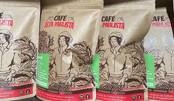 Pacotes de café Alta Paulista, marca de café artesanal de alta qualidade, com embalagem que apresenta uma ilustração de mulher e folhas, ideal para consumidores que buscam sabor original e aroma intenso. Rotas Gastronômicas do interior de SP.